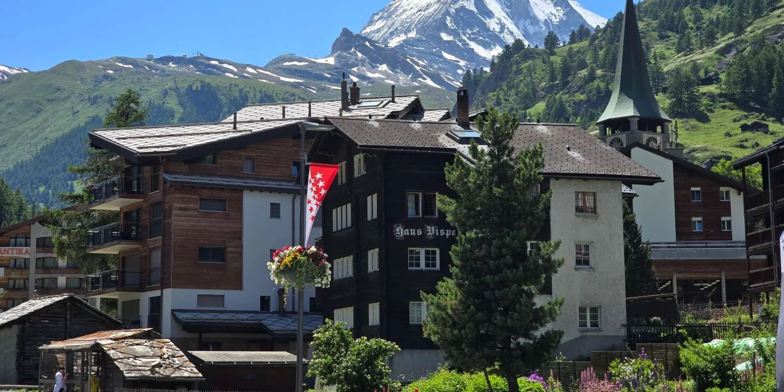 Chalets in central Zermatt flying the white-starred Valais flag, with the mountain rising behind