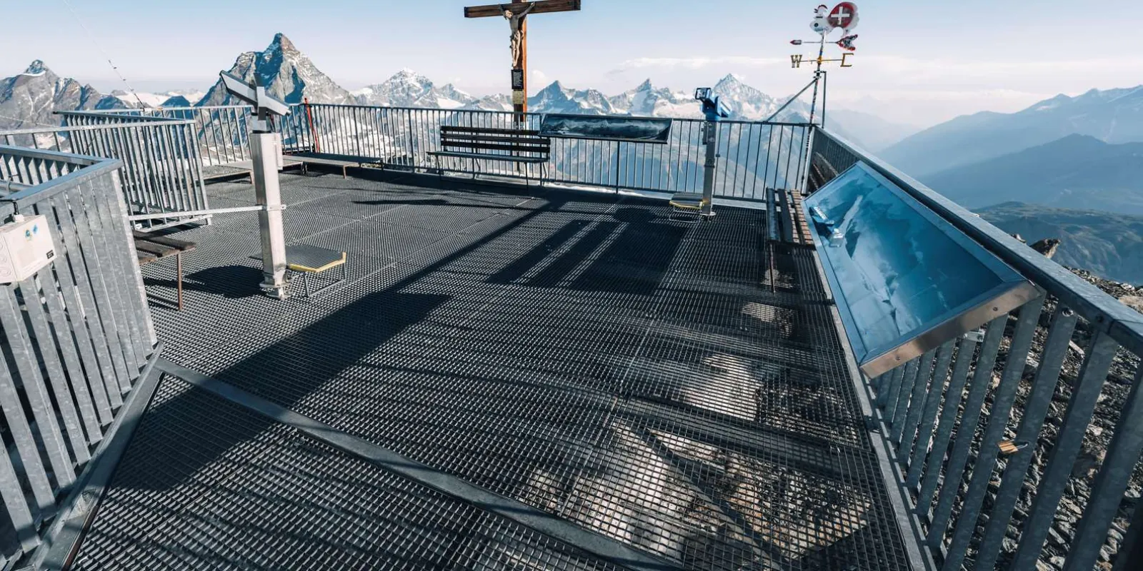 The open viewing platform at Matterhorn Glacier Paradise, with its summit cross and weather vane above a horizon of 4,000 m peaks