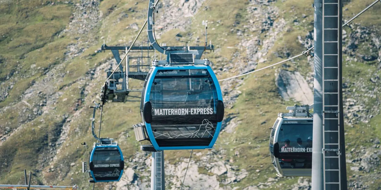 Blue Matterhorn Express gondolas climbing the slope above Zermatt towards Trockener Steg