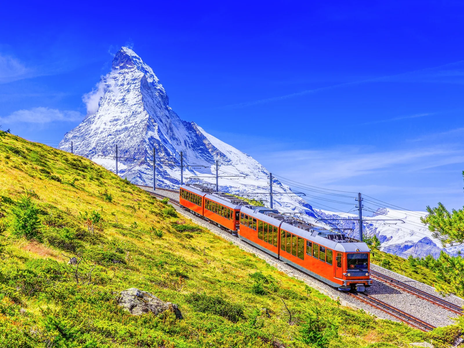 The Gornergrat train on the open mountainside with the Matterhorn filling the sky behind it