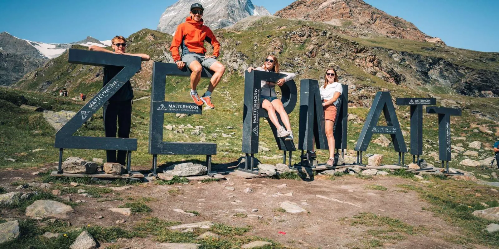 Travellers posing on the giant ZERMATT letters sculpture with the Matterhorn behind
