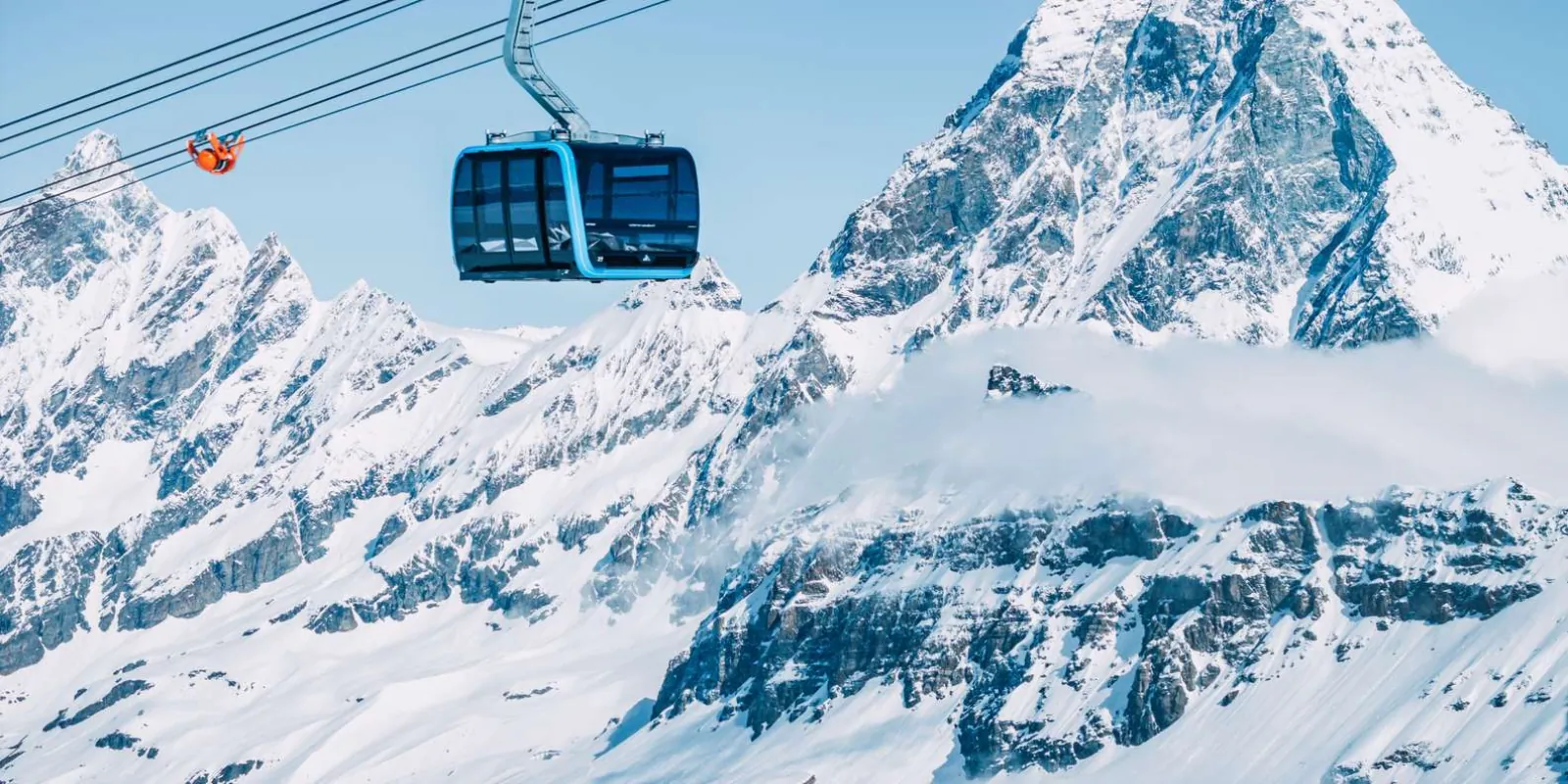 A cable-car cabin crossing high above snow-covered peaks on the Swiss-Italian border